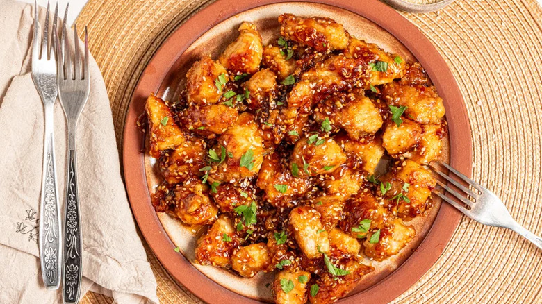 Sweet and spicy sesame chicken with herbs scattered on top