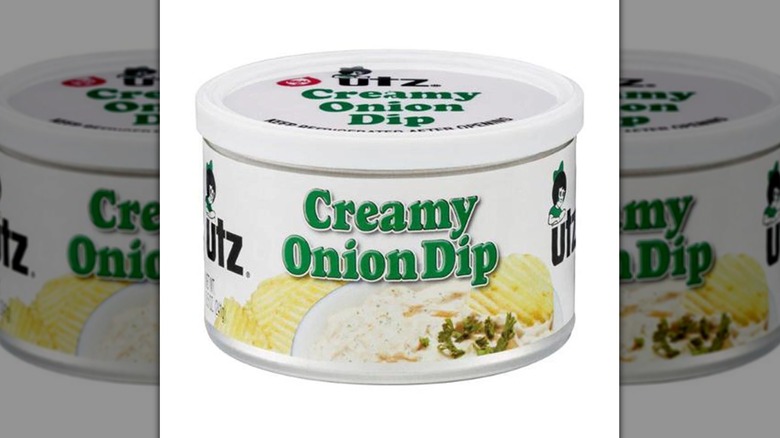White container of Utz creamy onion dip with white plastic lid on a white background.
