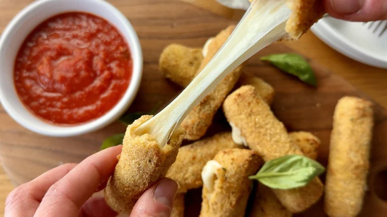 Mozzarella stick stringing melted cheese between broken halves