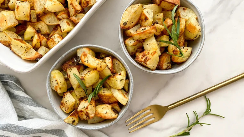 Bowls of roasted potatoes with fresh rosemary garnish