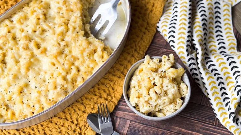 Macaroni and cheese in a casserole dish alongside a serving in a bowl.