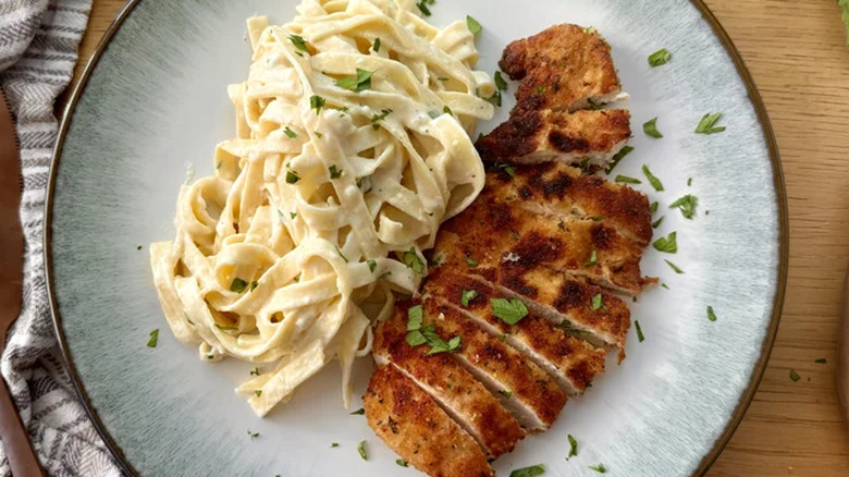 Chicken and Alfredo on a plate with herbs