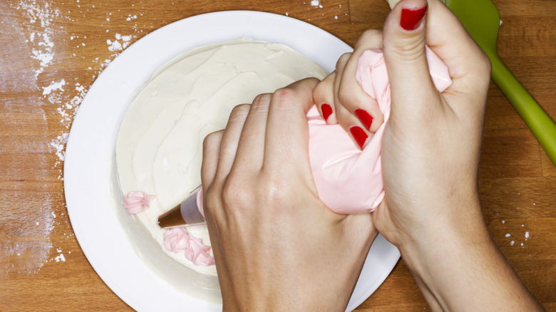 Piping frosting on a cake