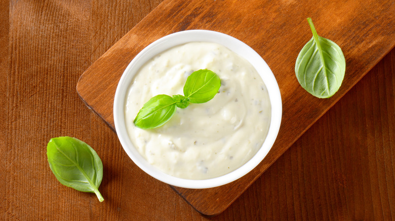 bowl of creamy salad dressing on a cutting board