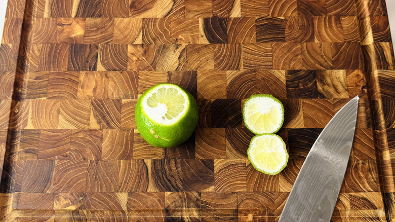 Lime with ends cut off on wooden board with knife