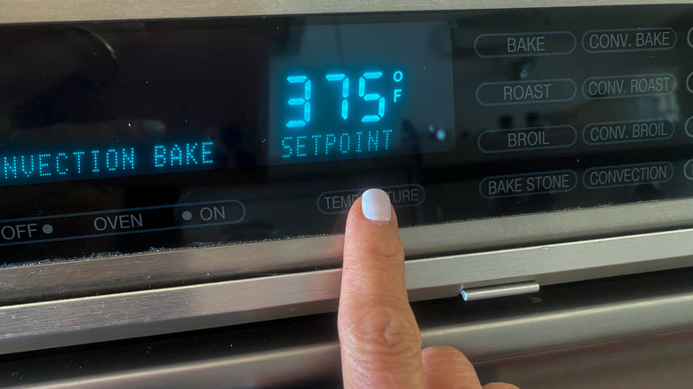 finger setting the oven temperature