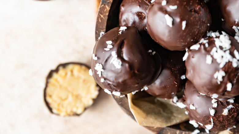 Peanut butter protein balls with a solid coating of chocolate and coconut shreds