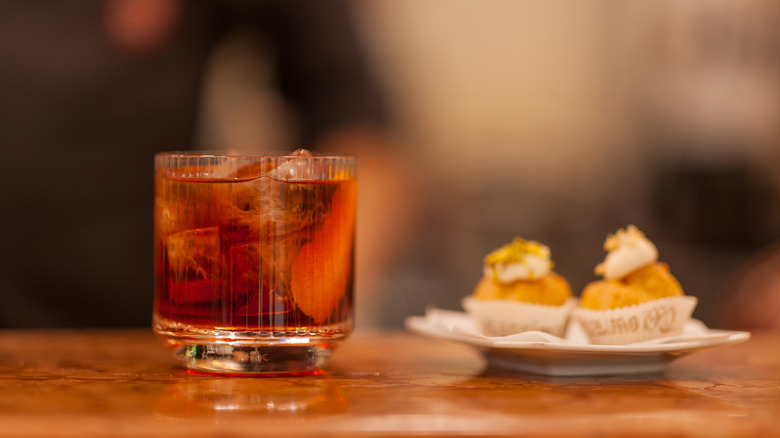 an Americano cocktail next to a plate with two dessert cups