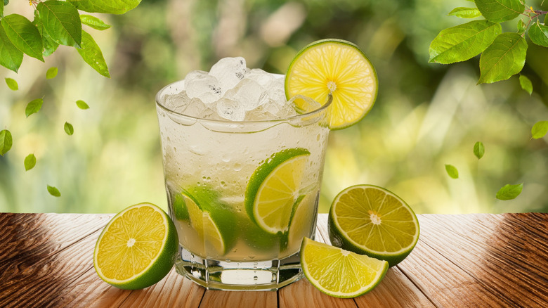 a caipirinha filled with crushed ice and sliced limes