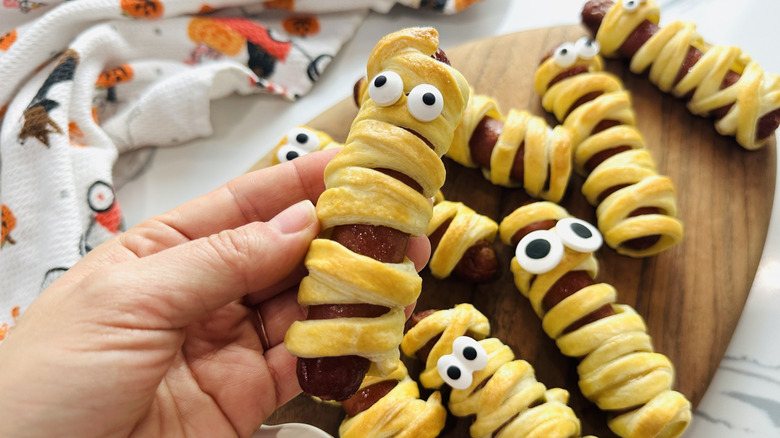 Hand holding mummy hot dog