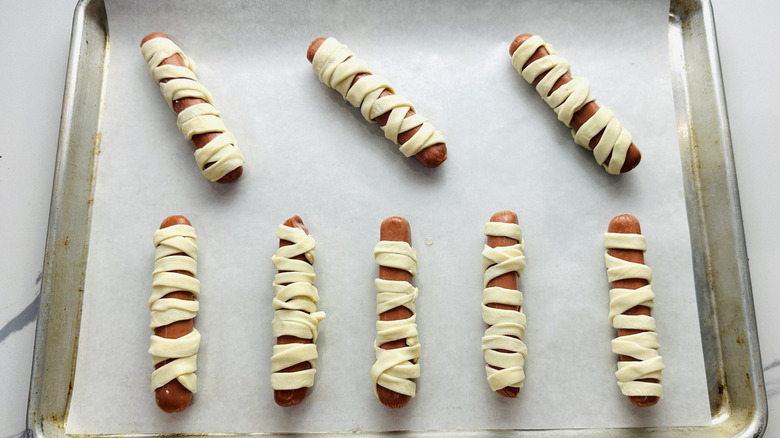 Mummy hot dogs on baking sheet