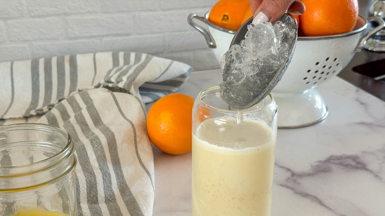 hand adding ice to glass with morir soñando
