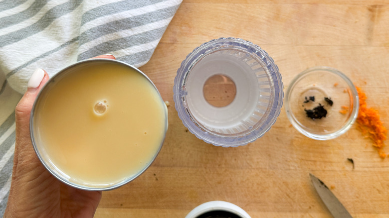 hand adding milk to blender