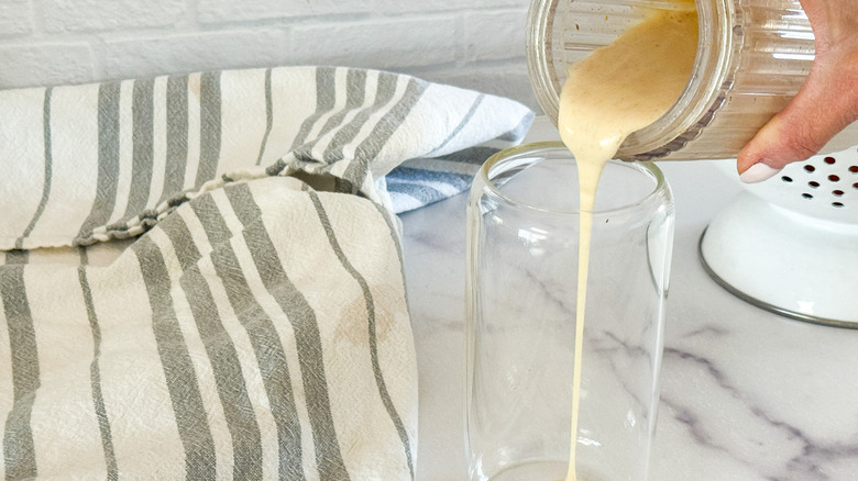 hand pouring milk into glass