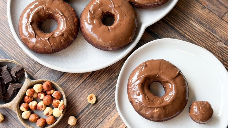 3-ingredient Nutella donuts on serving platter and plate with chocolate and hazelnuts