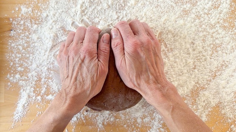 Kneading 3-ingredients Nutella donuts dough on floured surface