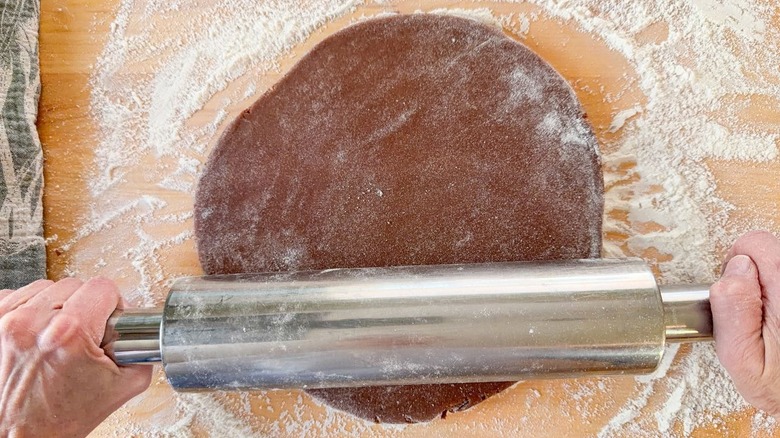 Rolling out 3-ingredient Nutella donuts dough on floured surface with rolling pin