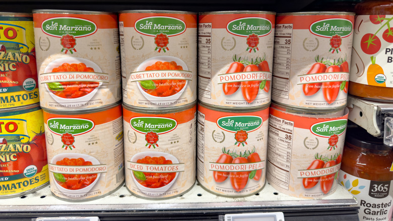 Cans of San Marzano tomatoes on a grocery store shelf.