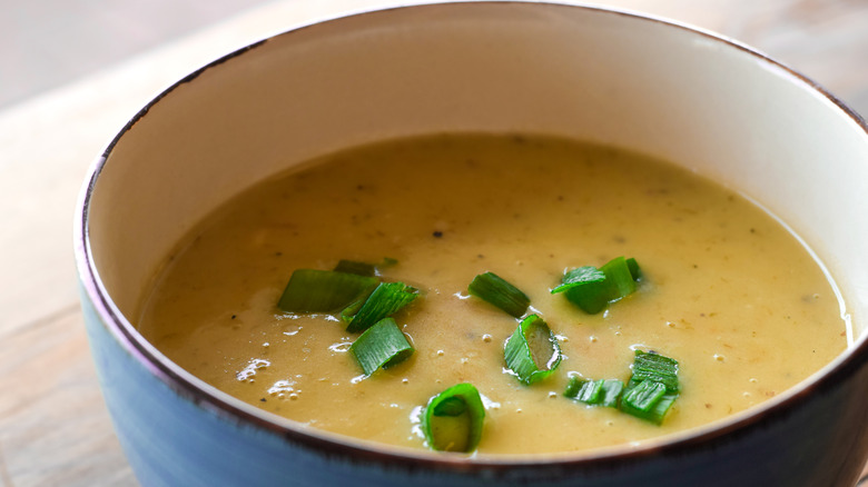 A bowl of potato soup garnished with spring onions.