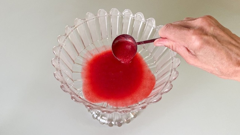 Using a ladle to add raspberry puree to a trifle dish