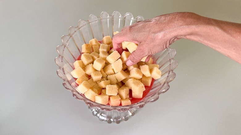 Adding poundcake cubes to trifle dish over raspberry puree