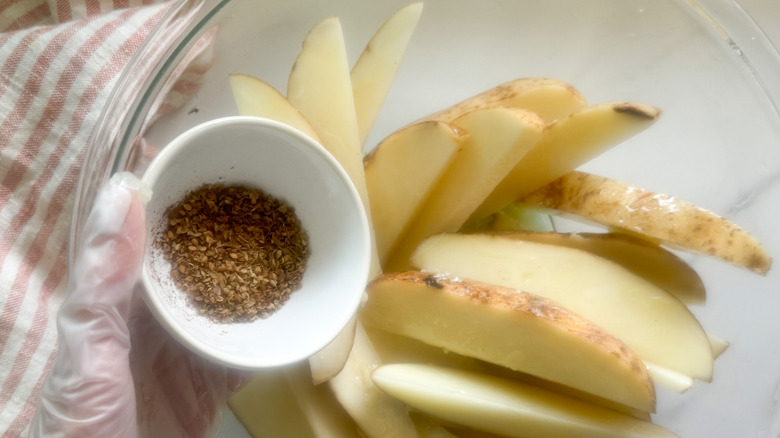 hand adding spices to wedges