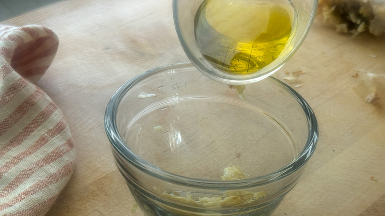 oil pouring into garlic bowl