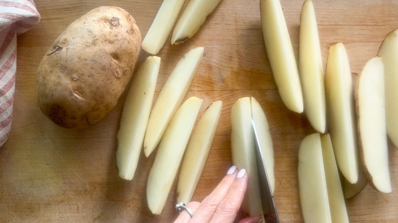 hand slicing potatoes into wedges