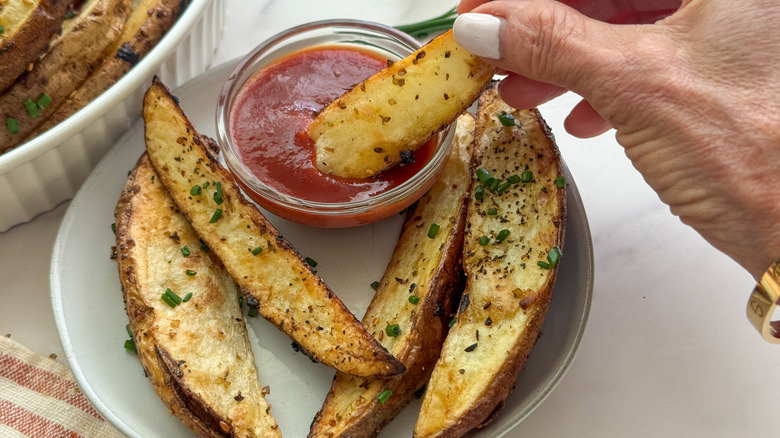 hand dipping wedge into ketchup