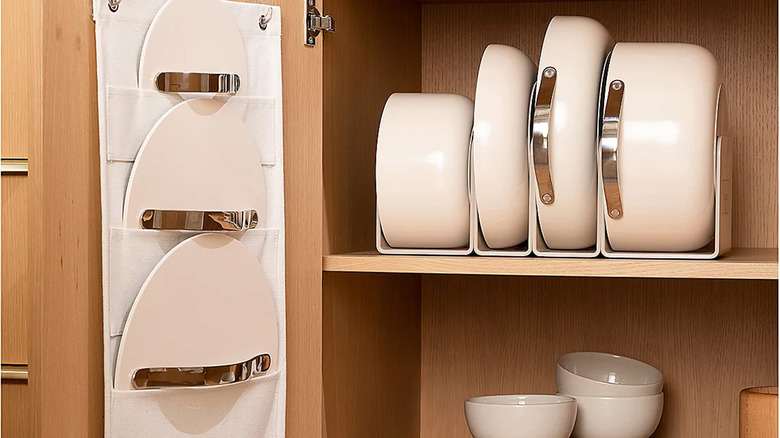 A Caraway Home Nonstick Ceramic Cookware Set in a kitchen cabinet.
