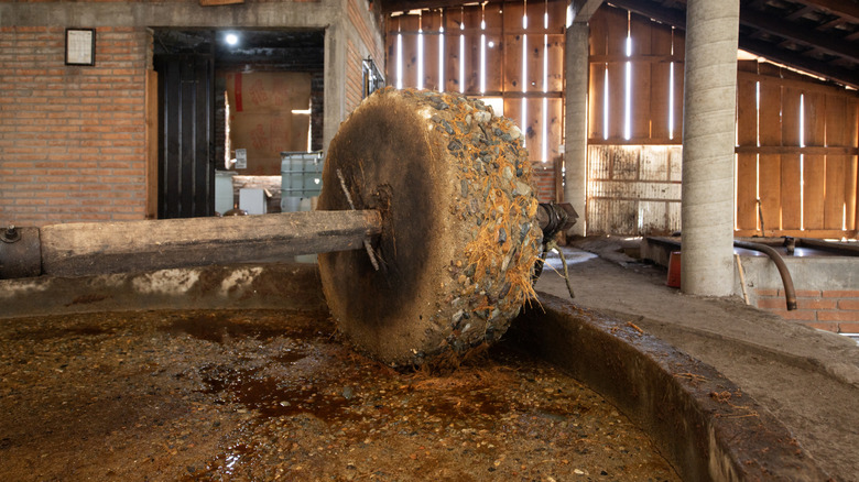 A large stone crushes agave leaves for mezcal production.