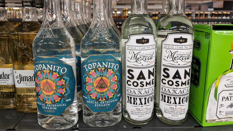 Bottles of artisanal mezcal sit on a store shelf.