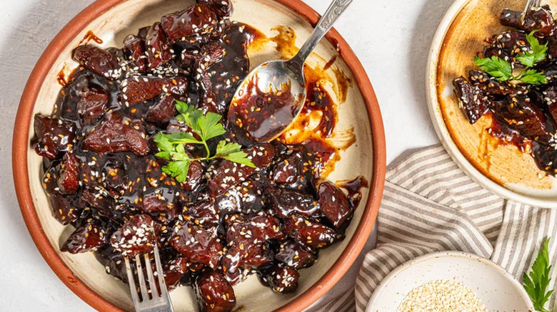 Sticky soy steak bites in a bowl with a spoon and a fork