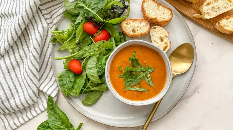 Tomato soup on a plate with bread and salad