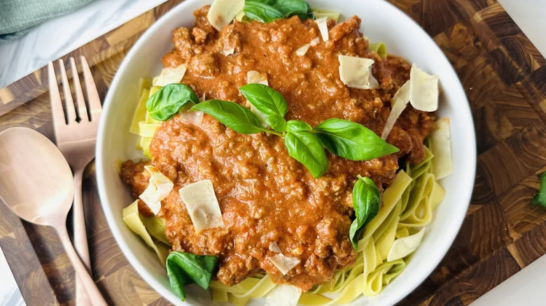Pasta in a bowl with basil and utensils