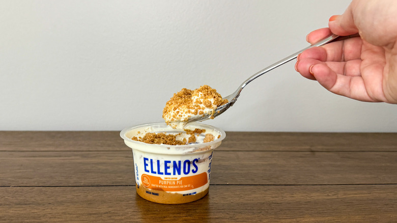 Hand holding a spoon scooping yogurt out of a container