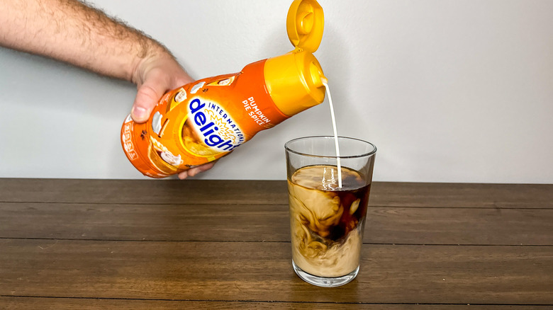 Hand pouring International Delight pumpkin pie spice coffee creamer