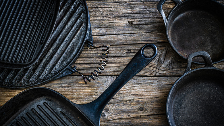 A variety of cast iron pans on a wooden tabletop
