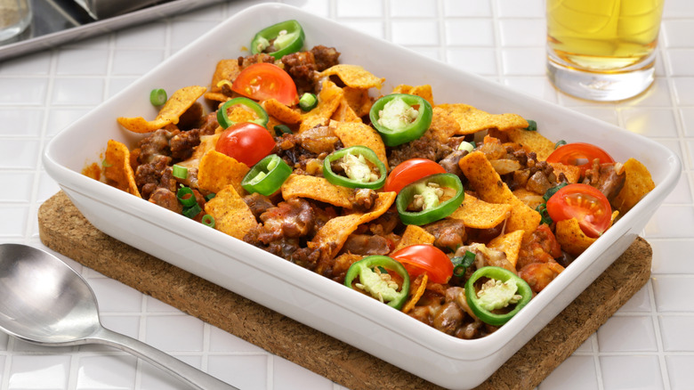 Frito chili pie bake in white casserole dish on counter surface.