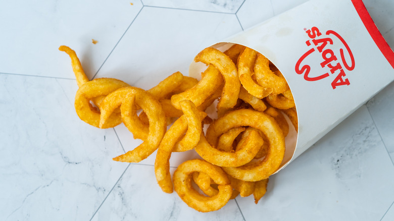 A small container of Arby's curly fries sitting on a white counter