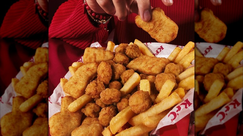 Woman taking a nugget out of a KFC basket of nuggets, popcorn chicken, and fries
