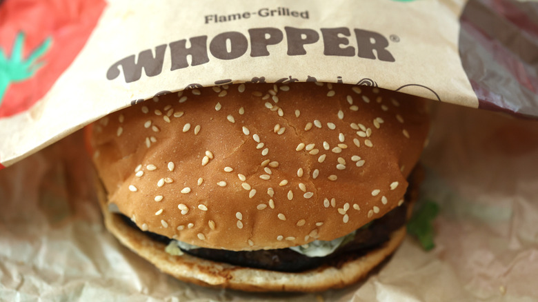 Whopper partially covered by wrapper