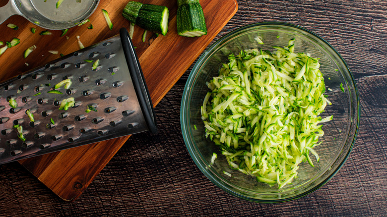a bowl of grated zucchini with a grater on the side