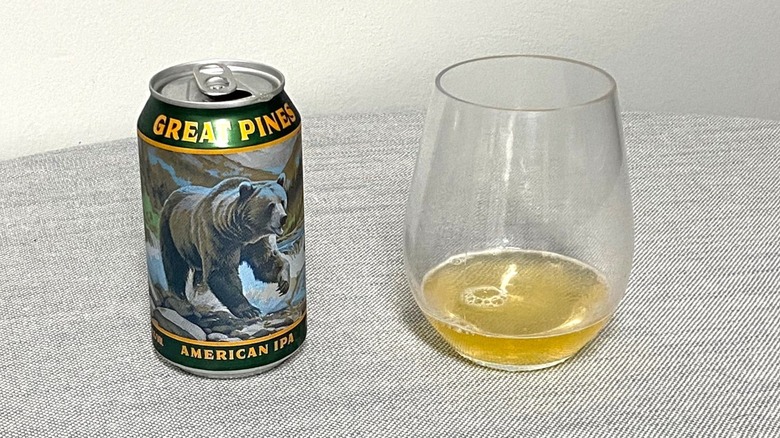 A can of Great Pines American IPA on a table beside a sample in a glass