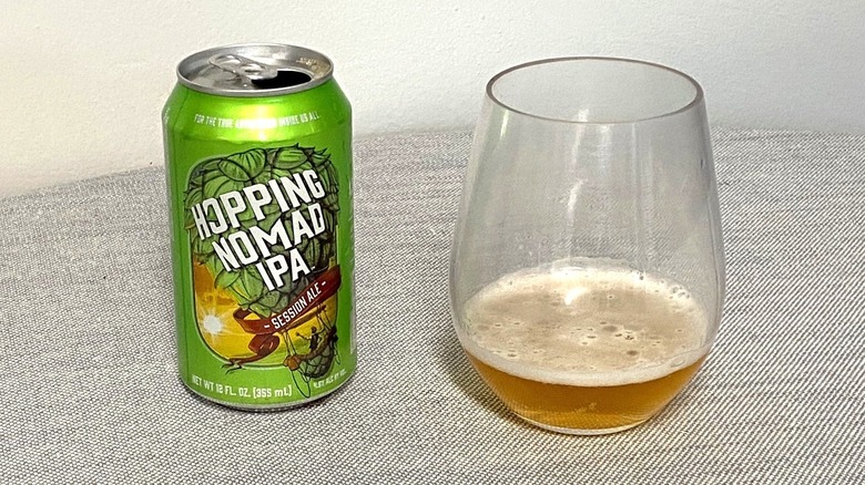 An open can of Hopping Nomad IPA next to a glass with a sample