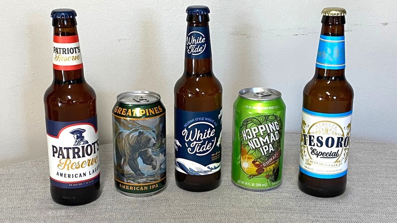 Five Aldi beers, three bottled and two canned, arranged on a table