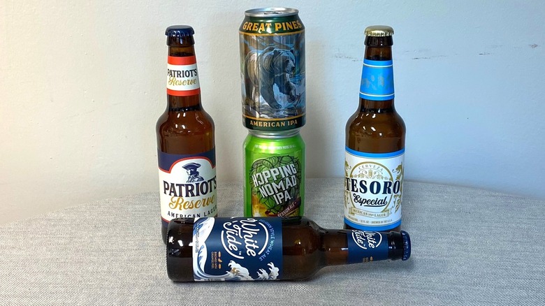 Five Aldi beers arranged on a table, with two cans stacked and one bottle laying down