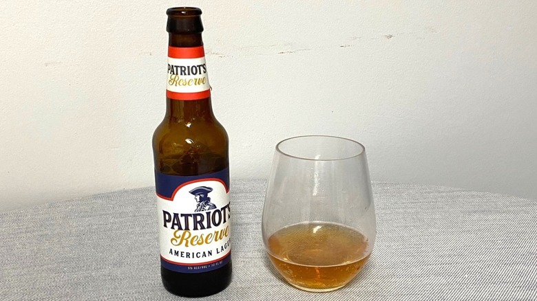 A bottle of Patriot's Reserve American Lager on a table beside a sample in a glass