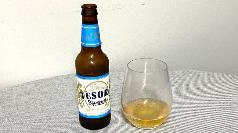 A bottle of Tesoro Especial beer on a table beside a sample in a glass