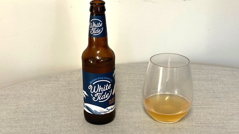 A bottle of White Tide beer on a table beside a sample in a glass